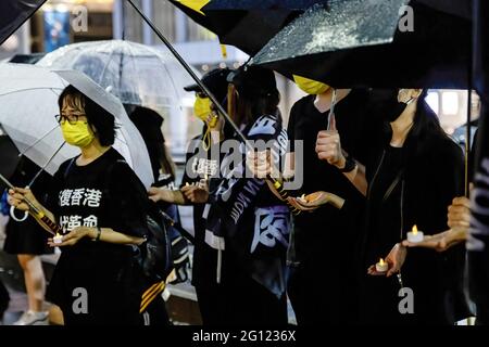 Tokio, Japan. Juni 2021. Während der Demonstration halten Demonstranten, die Masken tragen, Kerzen und Regenschirme. Prodemokratische Gruppen protestierten vor dem Bahnhof Shinjuku in Japan, um den 32. Jahrestag des Massakers auf dem Platz des Himmlischen Friedens zu begehen. Kredit: SOPA Images Limited/Alamy Live Nachrichten Stockfoto