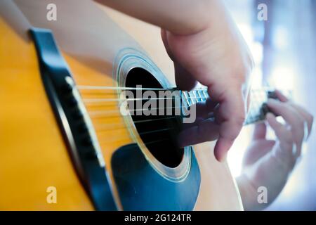 Männliche Hände spielen Finger Stil auf einer Western Dreadnought Gitarre in blauem Neonlicht Stockfoto