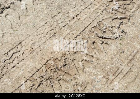 Schlammige Reifenspuren auf der Landstraße oder Feldeinfahrt. Denn, eine Spur hinterlassen, sich hinstecken, klar wie Schlamm, schlammig. Stockfoto