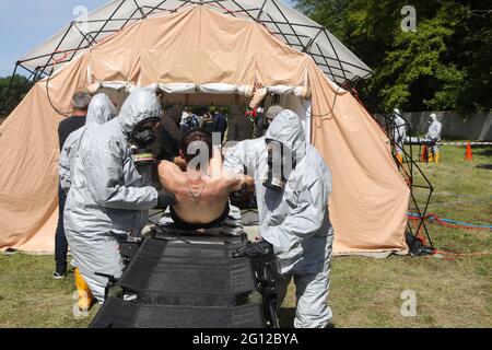 HAI, UKRAINE - 4. JUNI 2021 - Rettungskräfte in Schutzanzügen und Gasmasken legten einen Mann während der Spezialübungen des ukrainischen Staatlichen Notdienstes auf dem Trainingsgelände des Interregionalen Krisenreaktionszentrums, Dorf Hai, Region Sumy, im Nordosten der Ukraine, auf die Bahre. Kredit: Ukrinform/Alamy Live Nachrichten Stockfoto