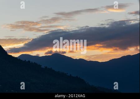 Licht, das durch das Wolkenfenster von untergehenden Sonnenstrahlen über den Gipfeln des Himalaya-Gebirges kommt. Dramatische Wolkenbildung - Himalaya, Indien. Stockfoto