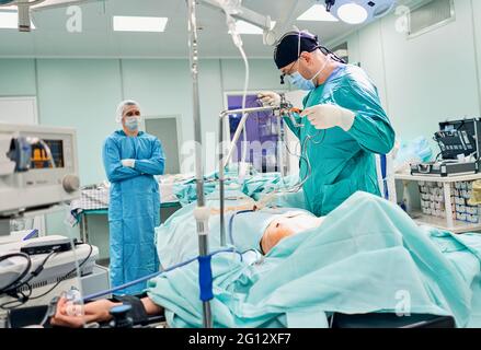 Gutaussehende Neurochirurgie harte Arbeit im professionellen Krankenhaus. Männlicher Chirurg, der im Operationsraum arbeitet. Stockfoto