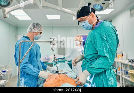 Gutaussehende Neurochirurgie harte Arbeit im professionellen Krankenhaus. Männlicher Chirurg, der im Operationsraum arbeitet. Stockfoto