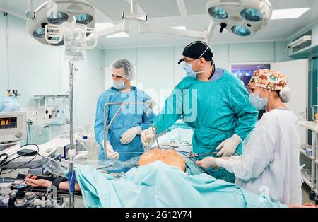 Gutaussehende Neurochirurgie harte Arbeit im professionellen Krankenhaus. Männlicher Chirurg, der im Operationsraum arbeitet. Stockfoto