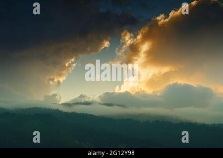 Licht, das durch das Wolkenfenster von untergehenden Sonnenstrahlen über den Gipfeln des Himalaya-Gebirges kommt. Dramatische Wolkenbildung mit Sonnenuntergangsfarben über Indian Mounta Stockfoto