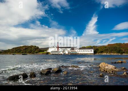 Ein Blick über die kleine Bucht zu den Gebäuden der Lagavulin Whiskybrennerei auf der Isle of Islay in Schottland. Stockfoto