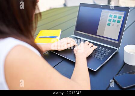 Nahaufnahme einer unkenntlichen Frau, die mit ihrem Computer im Freien arbeitet Stockfoto