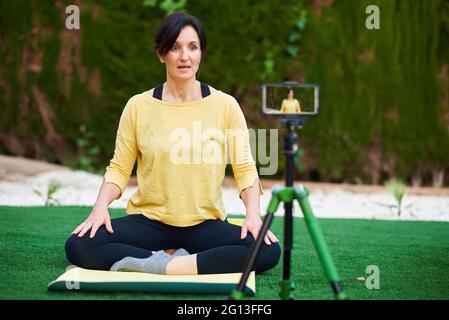 Eine weibliche Content-Creator zeichnet sich selbst beim Yoga für ihren Social-Media-Kanal auf Stockfoto