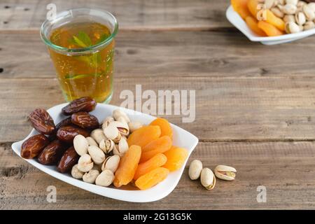 Auswahl an getrockneten Früchten mit einem Glas Minztee auf Holzboden. Speicherplatz kopieren. Stockfoto