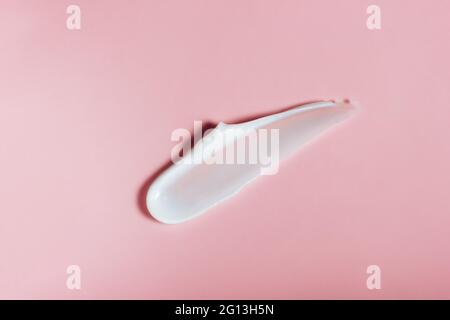 Weiße Hautcreme schmiert auf rosa Hintergrund. Hautpflegekonzept mit feuchtigkeitsspendenden Beauty-Produkten für die Gesichtsreinigung oder das Body SPA Stockfoto