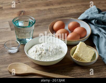 Backzutaten für die Herstellung von Pudding eclair Teig auf Holz Küchentisch Stockfoto