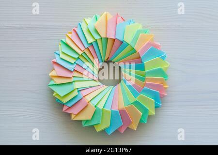 Origami, abstrakte parametrische Ringstruktur aus bunten Papierblättern, liegt auf einem weißen Schreibtisch, Draufsicht Stockfoto