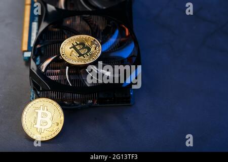 Bitcoin-Münze auf einer leistungsstarken Grafikkarte zum Mining und Sammeln von Kryptowährungskonzepten auf dunklem Hintergrund. Technologien der zukünftigen Währung. Oben Stockfoto
