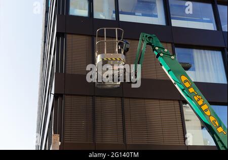 basel schweiz april 25. 2021: Erhöhte grüne Arbeitsplattform vor dem braunen Wolkenkratzer am Tag ohne Arbeit Stockfoto