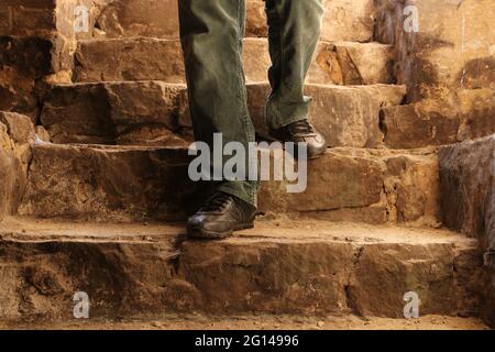 Ein Mann geht die Steintreppe hinunter zum Untergeschoss. Die alte Festung. Stockfoto