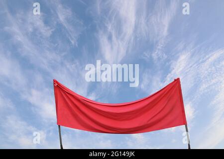 Ein Stück rotes Tuch gegen den blauen Himmel. Flugverbotskonzept. Coronavirus, COVID-19-Konzept. Digitale Komposition. Stockfoto