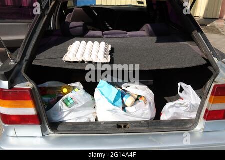 Plastiktüten mit Lebensmitteln im Kofferraum eines Autos. Aufgrund des Coronavirus kaufen Menschen Lebensmittel in großen Mengen. COVID-19. Stockfoto