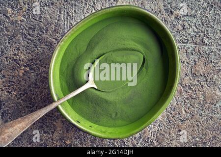 Gesundes Chlorella-Algenpulver in einer Schüssel und auf einem Löffel, Draufsicht Stockfoto