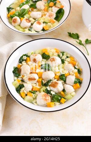 Italienische Hochzeitssuppe mit Fleischbällchen, Gemüse und kleinen Nudeln in einer Schüssel auf hellem Steingrund. Stockfoto