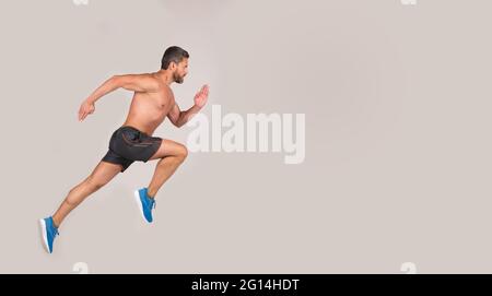 Sportler Mann Läufer laufen zum Erfolg oder springen hoch auf grauem Hintergrund, kopieren Raum, Sport Stockfoto