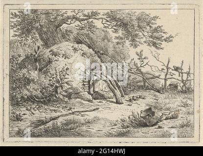 Backofen mit Besen. Das Gesicht auf dem halbrunden Ofen beim Baum. Ein Besen ist gegen den Ofen, ein zweiter Besen liegt auf dem Boden. Die Tür des Backofens ist mit einem gebogenen Baumstamm verschlossen. Stockfoto