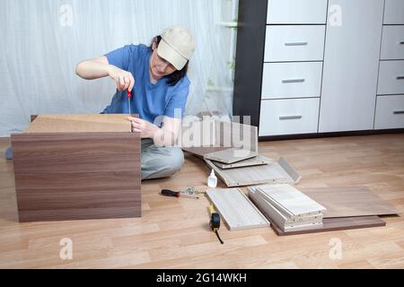 DIY Montage von flachverpackten Möbeln, reife Frau verschraubte Befestigungsschraube. Stockfoto