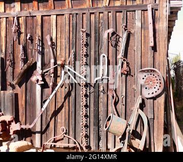 Veraltete landwirtschaftliche Werkzeuge hängen an der Außenseite des Schuppen Stockfoto