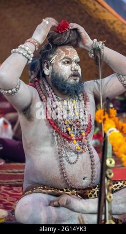 Haridwar, Uttarakhand, Indien 12. April 2021. Indische Heilige in ihrer traditionellen Art von Yog Mudra, meditierend. Schweigend sitzen als Teil der Initiation von neuem Sadhus während Kumbha Mela. Die Naga Sadhus. Stockfoto