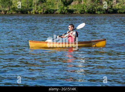 Ein junger Mann in einer Rettungsweste paddelt mit einem Kajak auf einem See in West Virginia Stockfoto