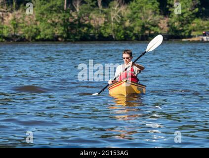 Ein junger Mann in einer Rettungsweste paddelt mit einem Kajak auf einem See in West Virginia Stockfoto