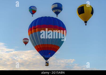 Sussex, NB, Kanada - 10. September 2016: Fünf bunte Heißluftballons steigen in der Dämmerung in die Luft. Der Himmel ist blau, aber teilweise bedeckt. Stockfoto