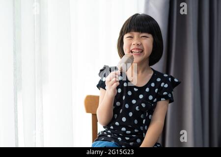 asiatische Mädchen essen Eis mit verschwommenem Hintergrund Stockfoto