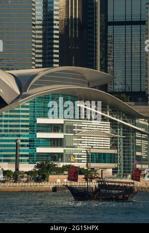 Das Aqua Luna, eine Nachbildung von chinesischem Müll, der für Kreuzfahrten verwendet wird, passiert das Kongress- und Ausstellungszentrum und die hohen Gebäude von Wan Chai, Hongkong Stockfoto