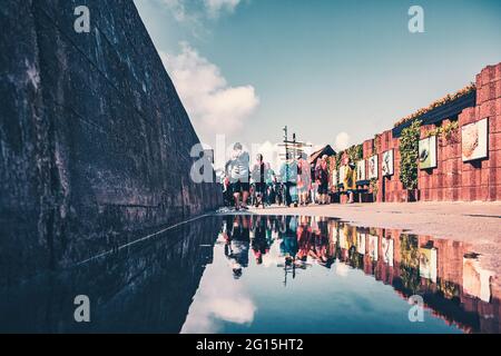 Reflexion in einer großen Pfütze von Touristen auf der Halbinsel Hel im Sommerurlaub. Island Hel Polen. Leute auf der Tourism Promenade. Stockfoto