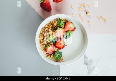 Flat Lay Food Konzept. Gesundes Frühstück. Weiße Nschüssel mit Joghurt, hausgemachtem Müsli, Erdbeeren Stockfoto