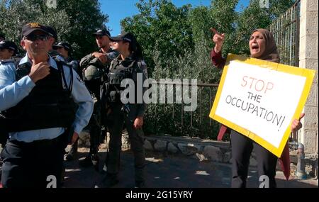 Eine Palästinenserin hält ein Plakat mit der Aufschrift „Stoppt die Besatzung“ während einer Demonstration gegen israelische Besatzung und Siedlungsaktivitäten in Scheich Jarrah, einem überwiegend palästinensischen Viertel, am 04. Juni 2021 in Jerusalem, Israel. Das palästinensische Viertel Sheikh Jarrah ist derzeit das Zentrum einer Reihe von Eigentumsstreitigkeiten zwischen Palästinensern und rechtsgerichteten jüdischen Israelis. Einige Häuser wurden nach einem Gerichtsurteil von israelischen Siedlern besetzt. Stockfoto