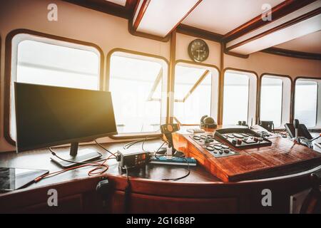 Ansicht eines Cockpitbereichs im Inneren eines Deckhauses einer modernen Safari- oder Kreuzfahrtyacht mit einem Bedienfeld auf dem Holzsockel und vielen Navigationsgeräten: c Stockfoto