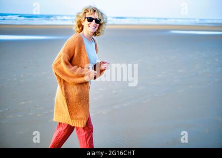 Junge reife blonde kaukasische Frau an einem sonnigen Tag draußen an einem Strand. Stockfoto