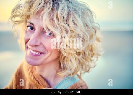 Junge reife blonde kaukasische Frau porträtiert im Freien an einem Strand. Stockfoto