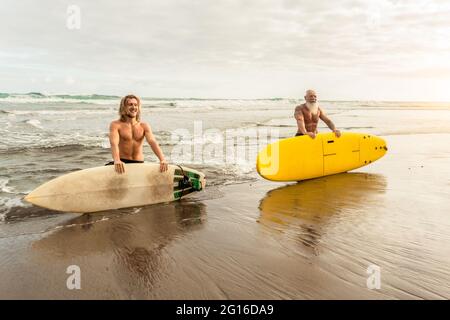 Fröhliche Freunde mit verschiedenen Alters surfen zusammen - Sportliche Menschen Spaß während des Urlaubs Surf Day - Extreme Sport Lifestyle Konzept Stockfoto