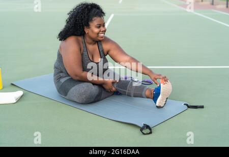 Kurvige Afro-Frau macht Stretching-Übungen - Junge afrikanische Frau hat Spaß beim Training im Freien - Sportliche Menschen Lifestyle-Konzept Stockfoto