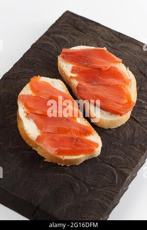 Zwei offene Sandwiches mit geräuchertem Lachs auf einem Holztablett Stockfoto