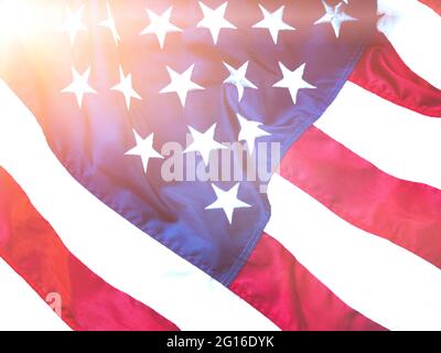 Amerikanische Flagge winkt im Wind mit blauem Himmel mit Streulicht und ist ein Symbol des Friedens. Militärische Symbole Konzept. Stockfoto