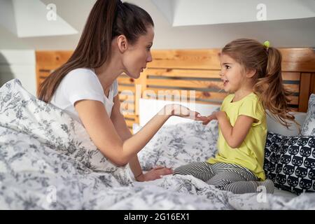 Ein kleines Mädchen, das an einem schönen Morgen im Schlafzimmer mit ihren Eltern im Bett spielt. Familie, zusammen, Liebe, Zuhause Stockfoto