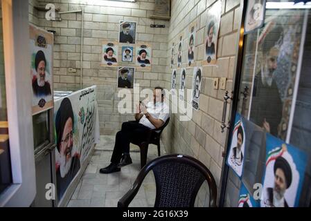 Teheran, Iran. Juni 2021. (6/4/2021) EIN Unterstützer eines Wahlkampfzentrums für den konservativen Politiker, den Chef der iranischen Justiz und den Präsidentschaftskandidaten Ebrahim Raisi vom Juni 18 sitzt hinter den Wahlplakaten der Raisi im Laden im Südwesten von Teheran. (Foto: Sobhan Farajvan/Pacific Press/Sipa USA) Quelle: SIPA USA/Alamy Live News Stockfoto