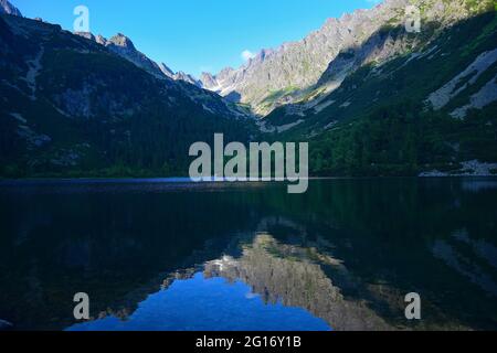 Die schöne Popradske pleso, umgeben von der Tatra, in der Abendsonne. Die Landschaft spiegelt sich im See wider. Slowakei. Stockfoto