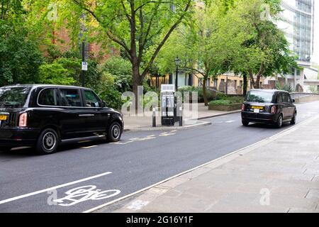 Schwarzes Taxi zum Aufladen des Fahrzeugs an einer elektrischen Ladestation in der City of London England, Großbritannien, KATHY DEWITT Stockfoto