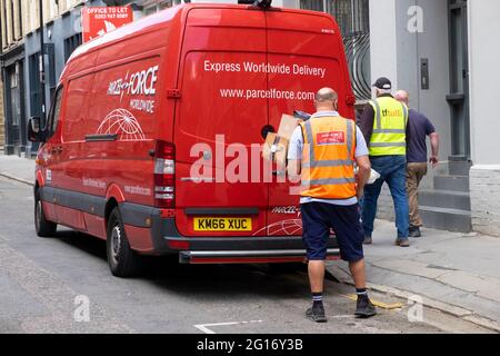 Rückansicht einer Mitarbeiterin der Paketdienste, die Pakete von einem roten Lieferwagen in einer Straße der Londoner City ablieferte London England Großbritannien KATHY DEWITT Stockfoto