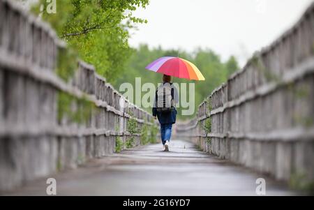 Bad Buchau, Deutschland. Juni 2021. Eine Frau mit Regenschirm auf der rund 1.5 Kilometer langen Federseebrücke am Federsee. Der Federsee bei Bad Buchau in Oberschwaben (Kreis Biberach) ist mit einer Fläche von rund 1.4 Quadratkilometern der zweitgrößte See in Baden-Württemberg. Quelle: Thomas Warnack/dpa/Alamy Live News Stockfoto