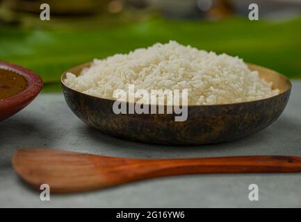 Gekochter Reis in abrassem Gefäß mit traditionellen Kerala-Beilagen im Hintergrund. Stockfoto